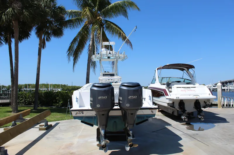 Slide: The Image of 2002 Contender 31 CC boat with twin engines, docked near palm trees and another boat. - 12