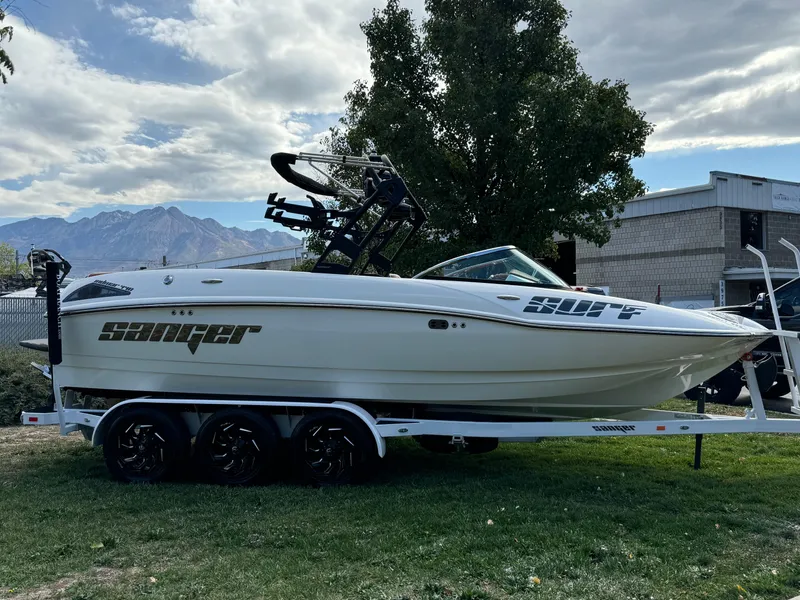 Slide: The Image of 2025 Sanger 231SL boat on trailer, parked on grass, with mountain backdrop. - 2