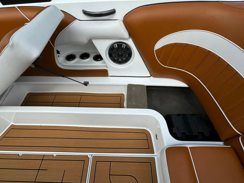 Slide: The Image of 2025 Sanger 231SL boat interior with brown and white seating, speaker, and teak flooring. - 26