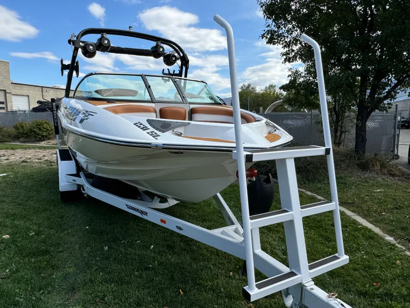 Slide: The Image of 2025 Sanger 231SL boat on trailer, parked on grass, with blue sky background. - 6