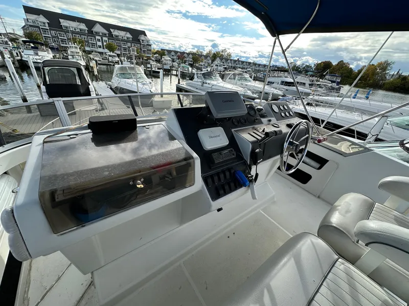 Slide: The Image of 1994 Carver 350 Aft Cabin Motor Yacht helm with marina view, featuring navigation equipment. - 8