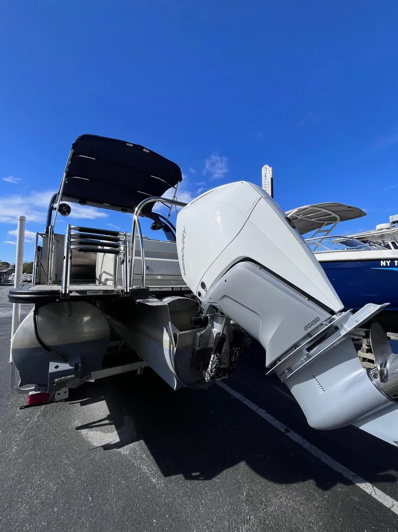 Slide: The Image of 2023 Avalon Excalibur Elite Windshield boat with powerful outboard motor, docked under clear blue sky. - 3