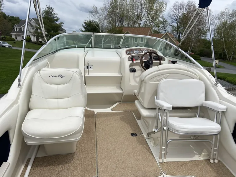 Slide: The Image of 2000 Sea Ray 245 Weekender boat interior with white seating and steering wheel. - 2
