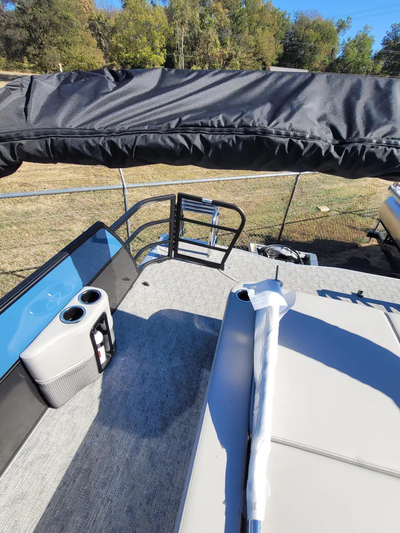Slide: The Image of 2025 Trifecta 24ULLET275 pontoon boat with seating and cup holders, docked outdoors. - 16