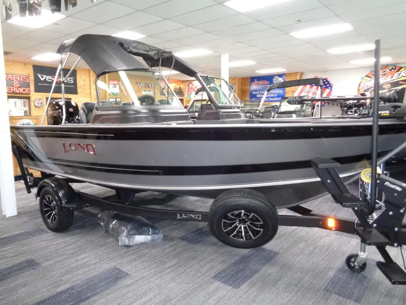 The Image of 2025 Lund 1875 Impact XS Sport boat displayed indoors on a trailer. - 1