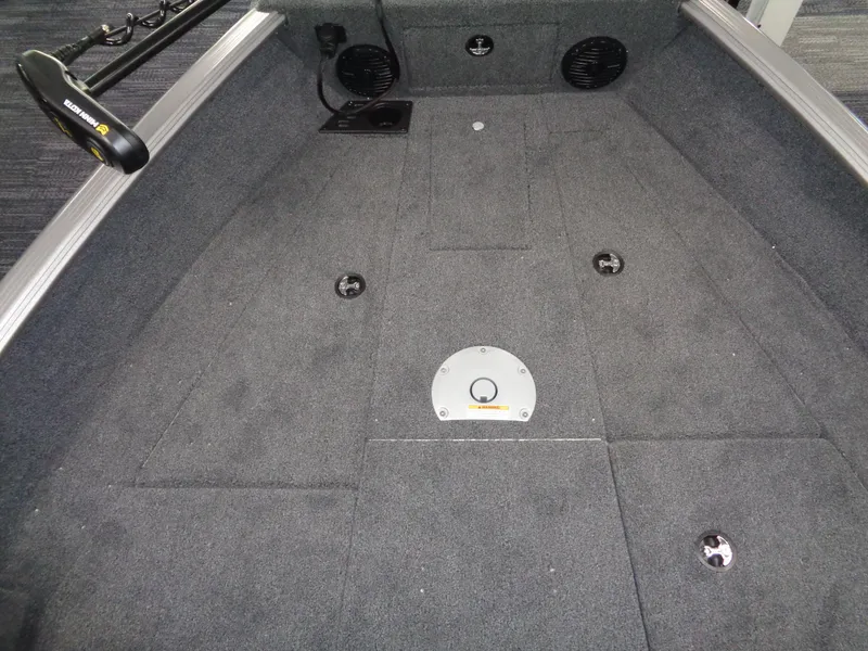 Slide: The Image of 2025 Lund 1875 Impact XS Sport boat interior with carpeted deck and mounted speakers. - 23