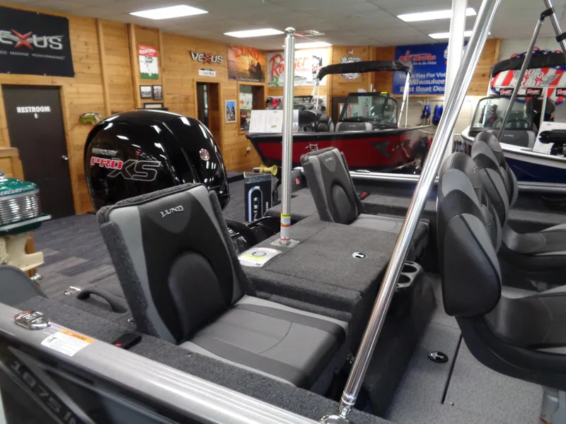 Slide: The Image of 2025 Lund 1875 Impact XS Sport boat interior with seating and motor in showroom. - 24