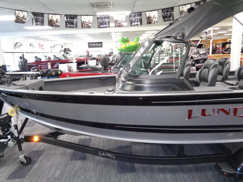 Slide: The Image of 2025 Lund 1875 Impact XS Sport boat in showroom, sleek design, gray and black exterior. - 31