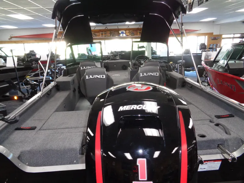 Slide: The Image of 2025 Lund 1875 Impact XS Sport boat with Mercury engine, displayed indoors. - 6