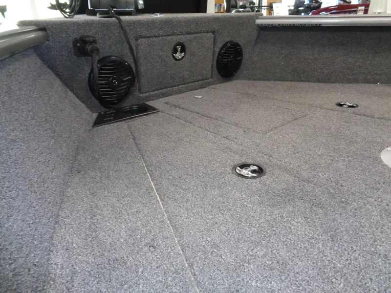 Slide: The Image of 2025 Lund 1875 Impact XS Sport boat interior with carpeted flooring and built-in speakers. - 9