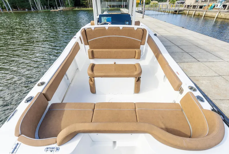 Slide: The Image of 2025 Sea Hunt Ultra 235 SE boat interior with tan seating, docked by the water. - 11