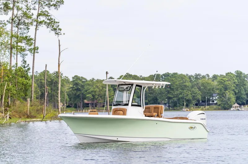 Slide: The Image of 2025 Sea Hunt Ultra 235 SE boat on a serene lake with forested background. - 13