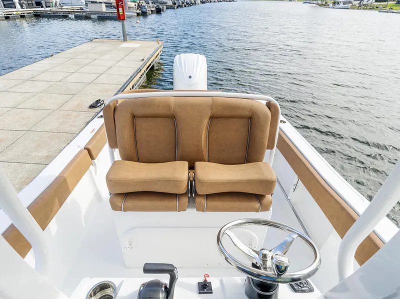 Slide: The Image of 2025 Sea Hunt Ultra 235 SE boat interior with tan seating and steering wheel by the dock. - 3