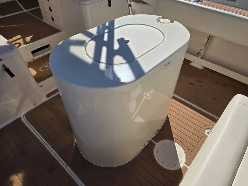 Slide: The Image of 2009 Grady-White Marlin 300 boat interior with white storage compartment on wooden deck. - 26