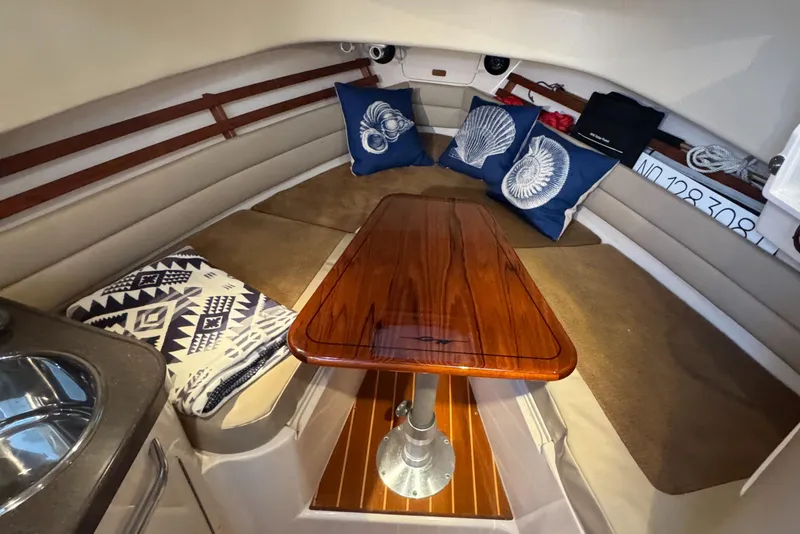 Slide: The Image of 2009 Grady-White Marlin 300 cabin interior with wood table and nautical-themed cushions. - 33