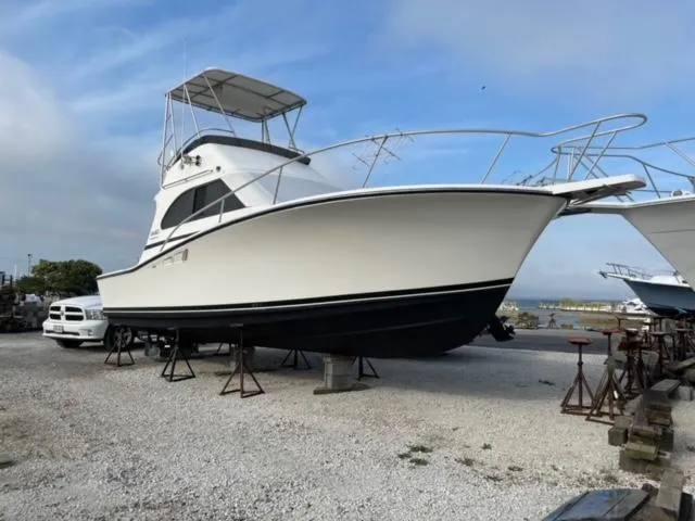 Slide: The Image of 1989 Luhrs 320 Tournament boat on dry dock, white hull, blue sky background. - 0