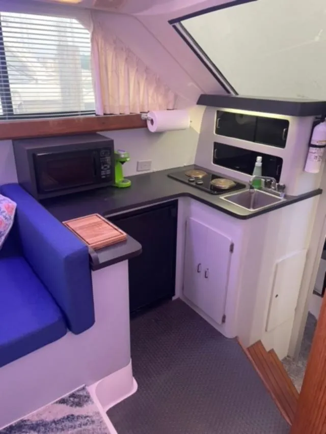 Slide: The Image of 1989 Luhrs 320 Tournament boat interior with kitchenette, featuring microwave, sink, and seating area. - 13
