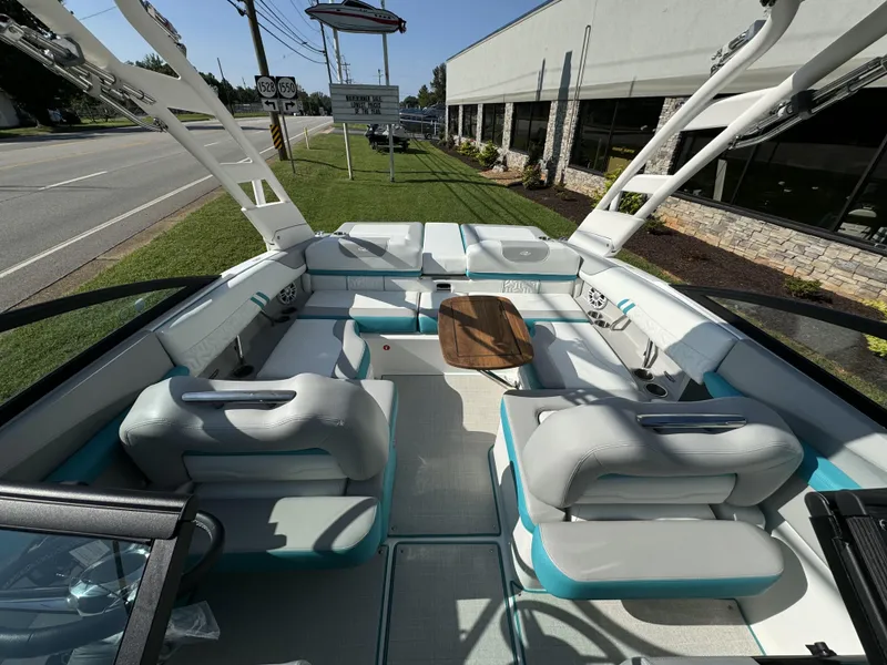 Slide: The Image of 2025 Regal LS2 boat interior with modern seating and wooden table, parked near a road. - 13