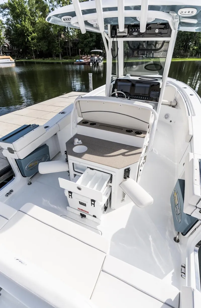 Slide: The Image of 2025 Sea Hunt Ultra 275 SE boat interior with seating and storage, docked by a lake. - 42