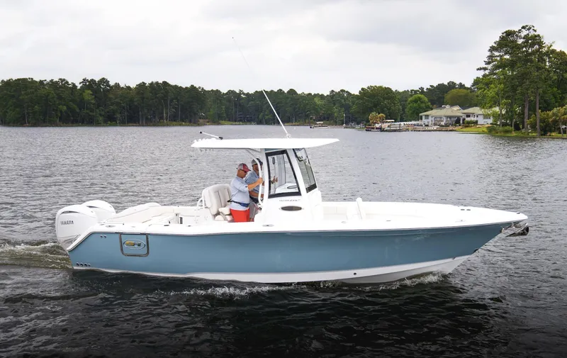Slide: The Image of 2025 Sea Hunt Ultra 275 SE boat cruising on a lake with lush green shoreline. - 45