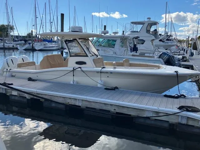 Slide: The Image of 2021 Scout 277 LXF boat docked in marina with other yachts. - 2