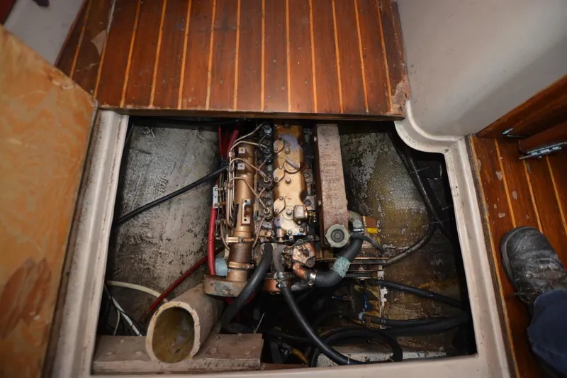 Slide: The Image of Engine compartment of 1986 Capital Gulf Pilothouse with visible mechanical components and wooden flooring. - 21