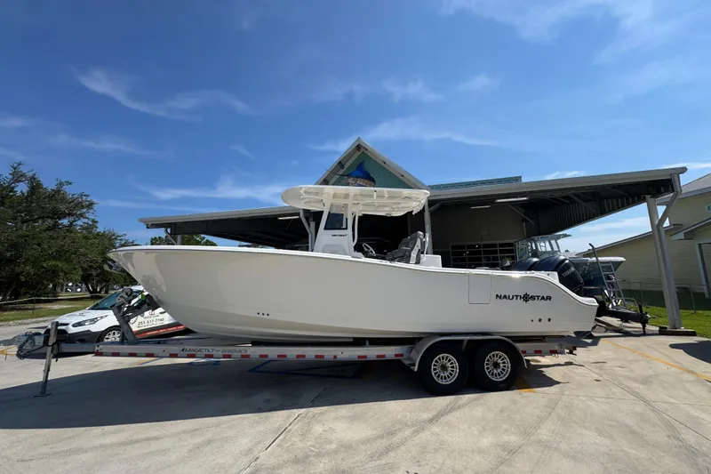 Slide: The Image of 2024 NauticStar 292 Legacy boat on trailer, parked outdoors under clear blue sky. - 1