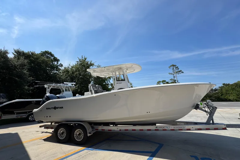 Slide: The Image of 2024 NauticStar 292 Legacy boat on trailer under clear blue sky. - 10