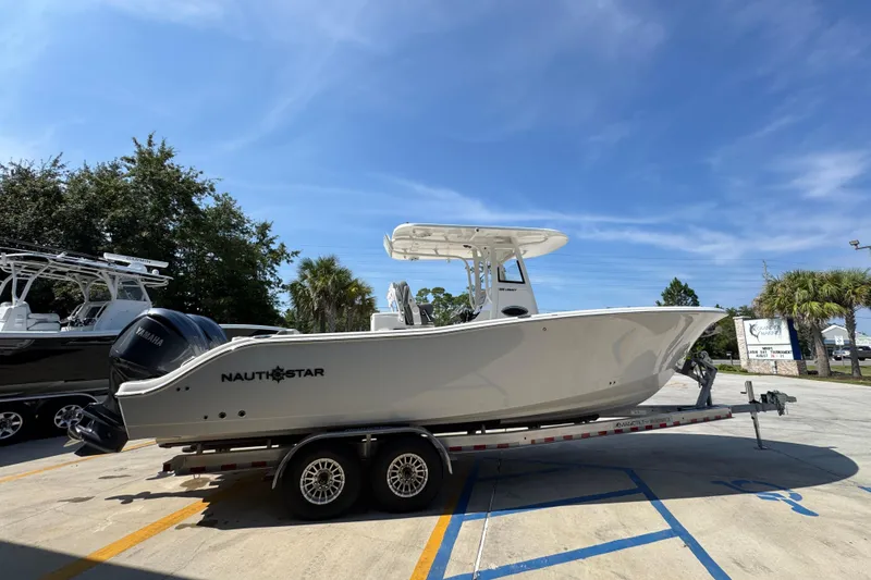 Slide: The Image of 2024 NauticStar 292 Legacy boat on trailer under clear blue sky. - 11