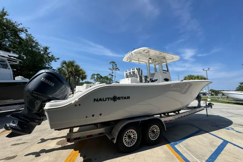 Slide: The Image of 2024 NauticStar 292 Legacy boat on trailer, featuring Yamaha engine, under clear blue sky. - 12