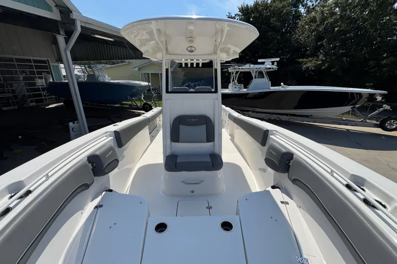 Slide: The Image of 2024 NauticStar 292 Legacy boat interior with seating and console, docked outdoors. - 23