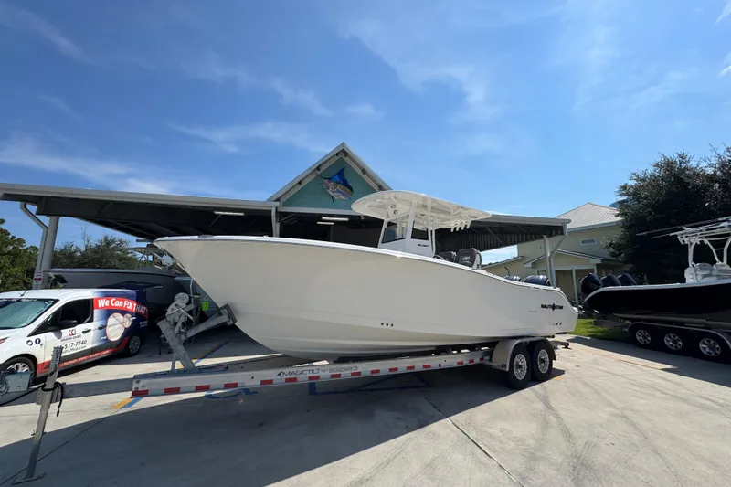 Slide: The Image of 2024 NauticStar 292 Legacy boat on trailer, parked outside a building under a clear sky. - 3