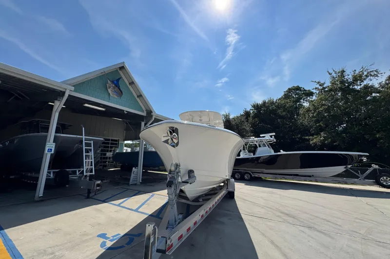Slide: The Image of 2024 NauticStar 292 Legacy boat on trailer at marina under clear blue sky. - 6