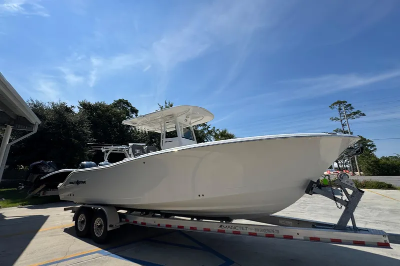 Slide: The Image of 2024 NauticStar 292 Legacy boat on trailer under clear blue sky. - 9