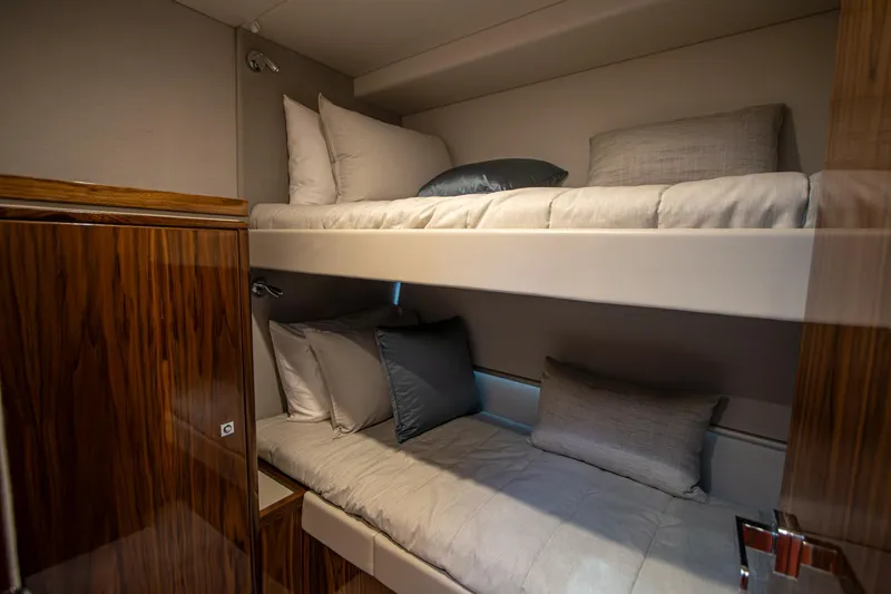 Slide: The Image of Luxurious 2024 Riviera 4600 SY yacht cabin with cozy bunk beds and elegant wood finish. - 10