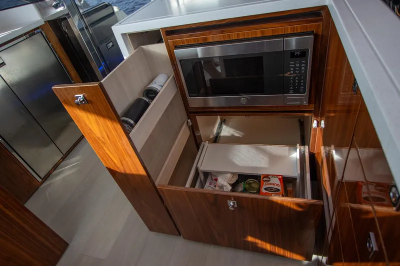 Slide: The Image of Modern kitchen in 2024 Riviera 4600 SY yacht with microwave and storage drawers. - 12