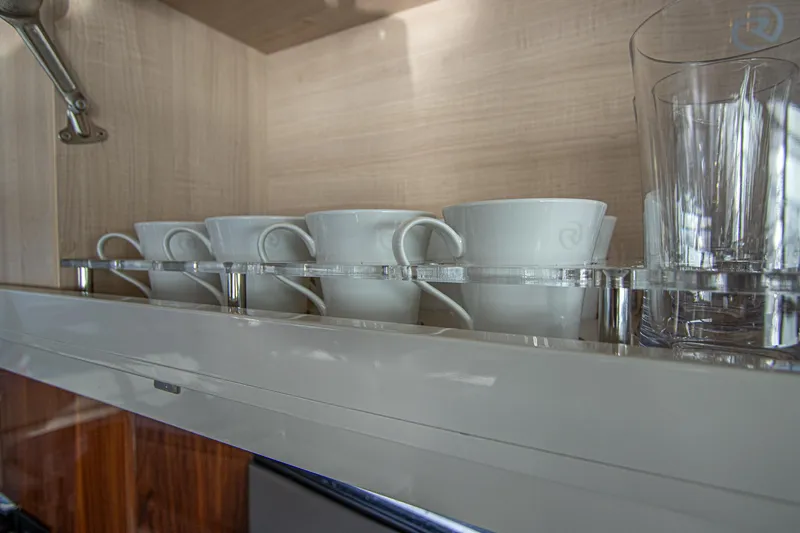Slide: The Image of White cups and glasses neatly arranged in a cabinet on a 2024 Riviera 4600 SY yacht. - 40