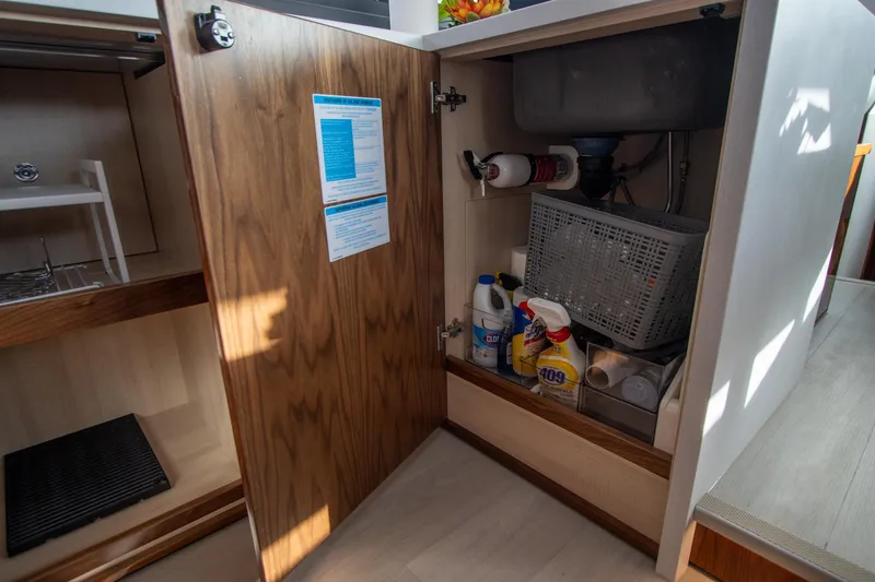 Slide: The Image of Open cabinet in 2024 Riviera 4600 SY yacht, storing cleaning supplies and equipment. - 44