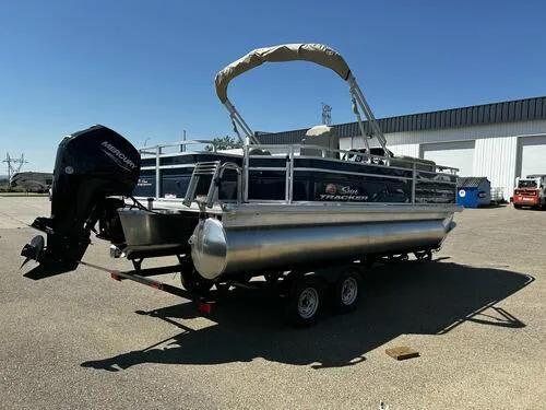 Slide: The Image of 2025 Sun Tracker Fishin' Barge 20 DLX pontoon boat on trailer, parked outdoors. - 3