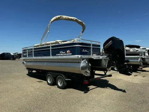 Slide: The Image of 2025 Sun Tracker Fishin' Barge 20 DLX pontoon boat on trailer, outdoor setting. - 4