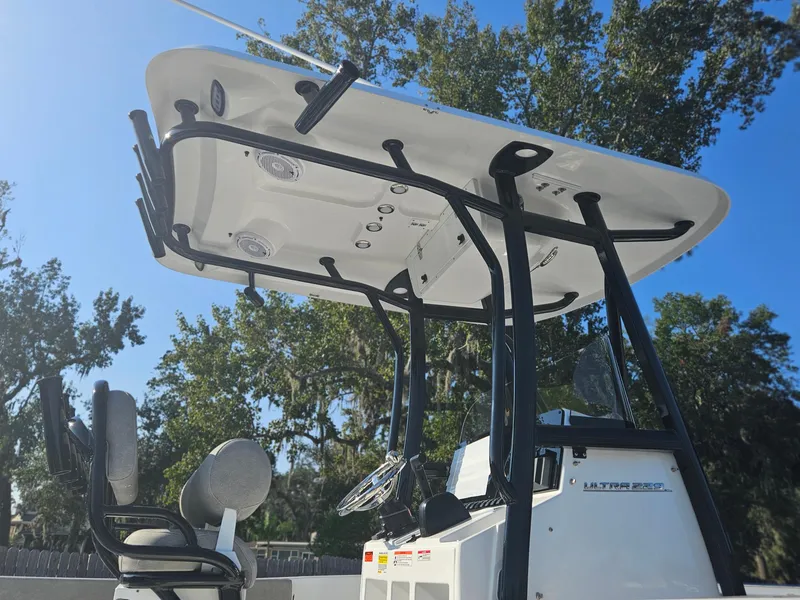 Slide: The Image of 2025 Sea Hunt Ultra 229 boat with T-top and seating, under clear blue sky. - 10