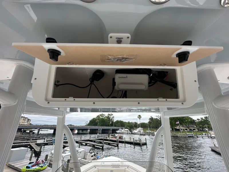 Slide: The Image of 2025 Sea Hunt Ultra 229 boat console with open storage compartment at marina. - 12
