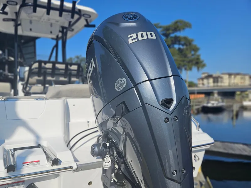 Slide: The Image of 2025 Sea Hunt Ultra 229 boat with Yamaha 200 outboard motor, docked by the water. - 2
