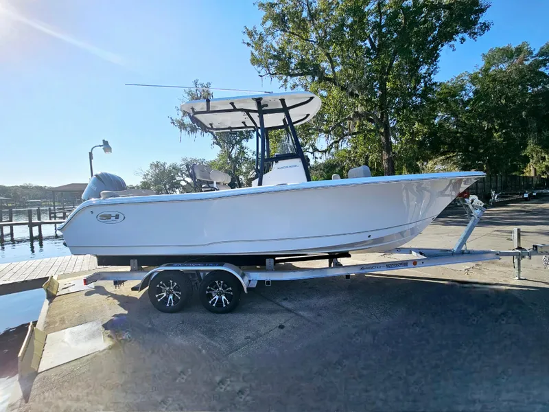 Slide: The Image of 2025 Sea Hunt Ultra 229 boat on trailer, parked near a dock under clear blue sky. - 8