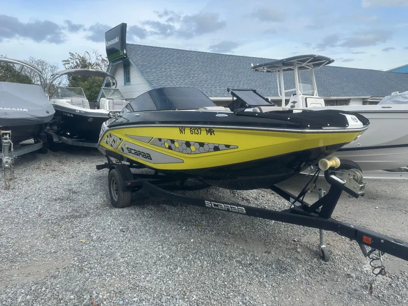The Image of 2020 Scarab 195 ID boat in yellow and black on a trailer, parked outdoors. - 1
