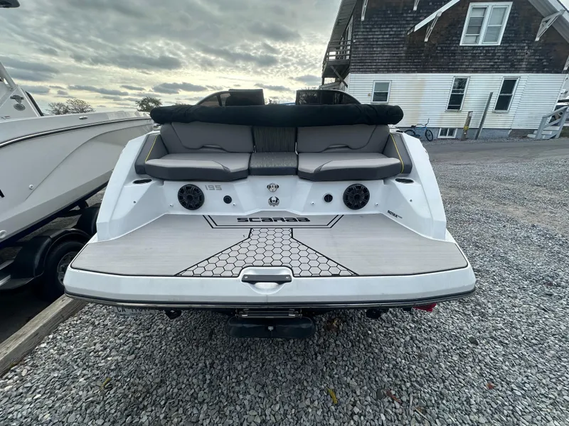 Slide: The Image of 2020 Scarab 195 ID boat, rear view, white exterior, docked on gravel. - 7