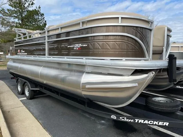 The Image of 2025 Sun Tracker SportFish 22 XP3 pontoon boat on trailer, parked outdoors. - 0
