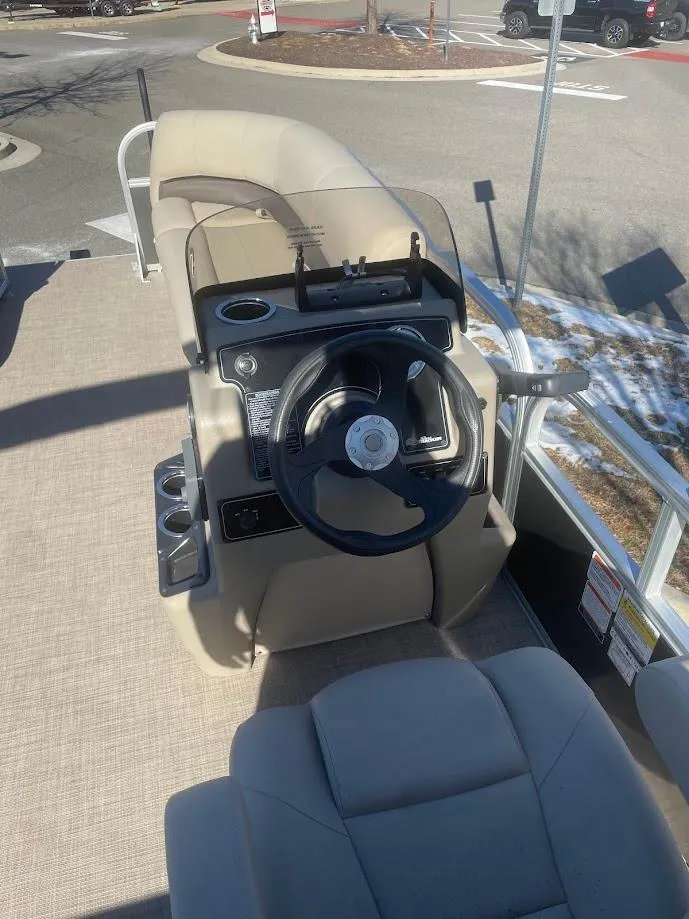 Slide: The Image of 2025 Sun Tracker Party Barge 16 DLX boat interior with steering wheel and seating. - 2