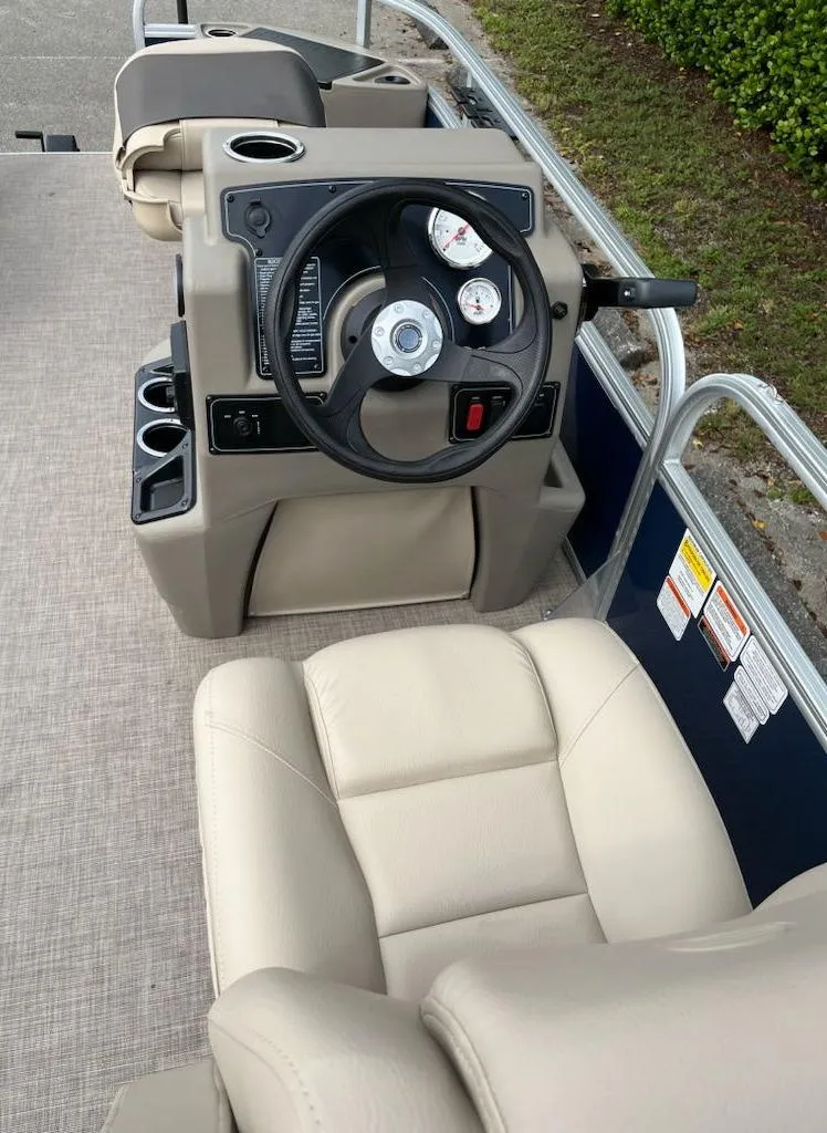 Slide: The Image of 2025 Sun Tracker Bass Buggy 18 DLX boat interior with steering wheel and beige seating. - 3