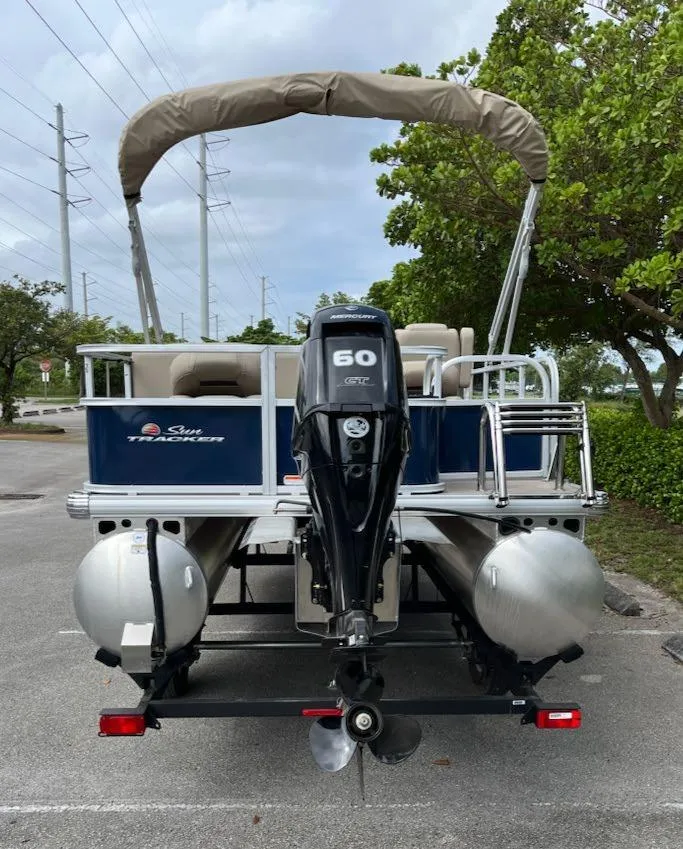 Slide: The Image of 2025 Sun Tracker Bass Buggy 18 DLX pontoon boat with 60 HP engine, parked outdoors. - 4
